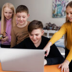 Four kids using a laptop and doing coding